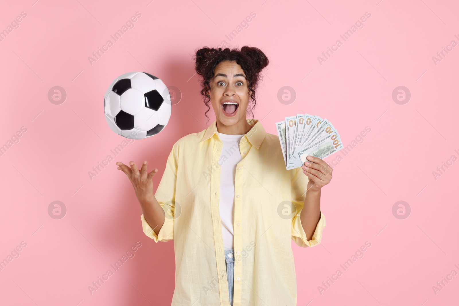 Photo of Happy woman with money throwing soccer ball on pink background