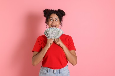 Happy woman with dollar banknotes on pink background