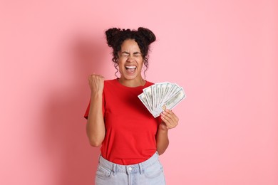 Happy woman with dollar banknotes on pink background