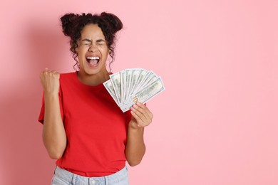 Happy woman with dollar banknotes on pink background, space for text