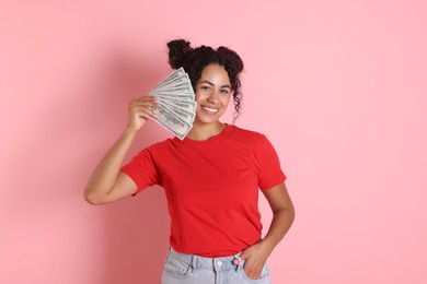 Happy woman with dollar banknotes on pink background