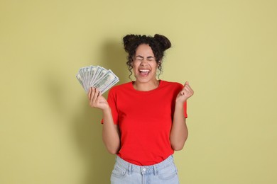 Happy woman with dollar banknotes on pale green background