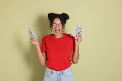 Happy woman with dollar banknotes on pale green background