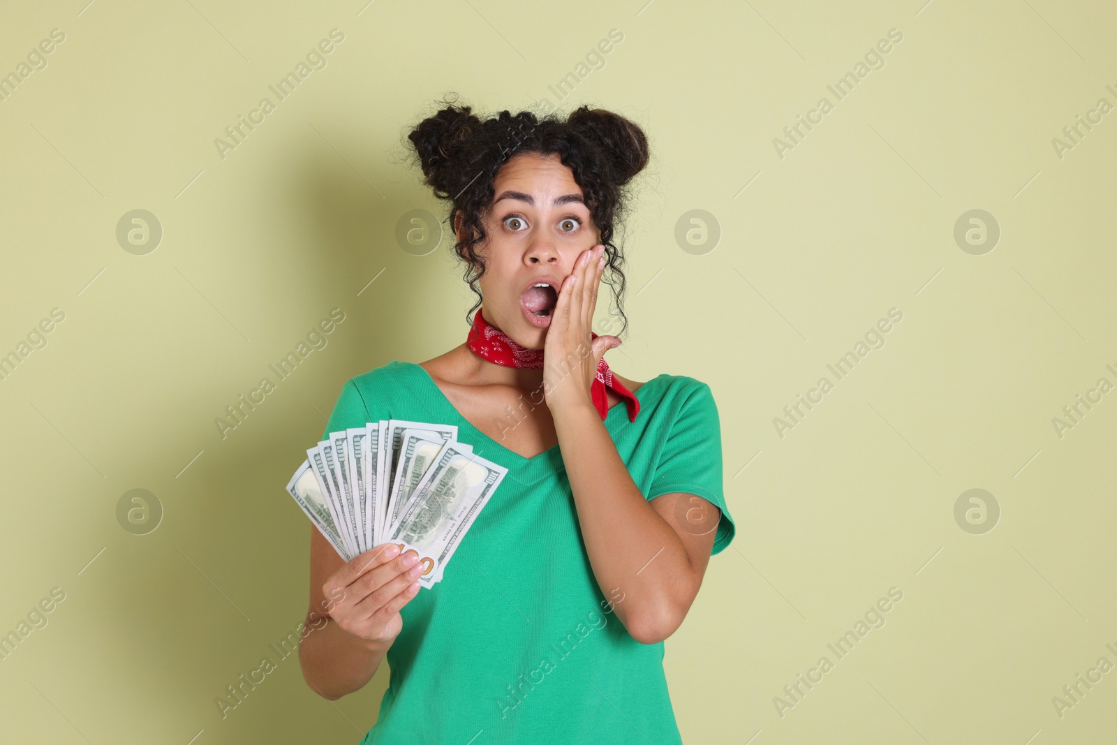 Photo of Shocked woman with dollar banknotes on pale green background