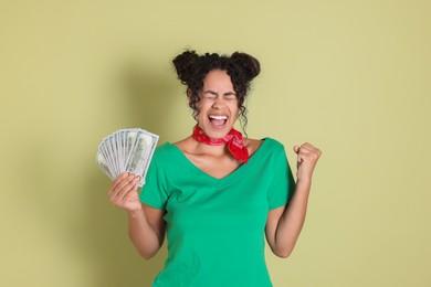 Happy woman with dollar banknotes on pale green background