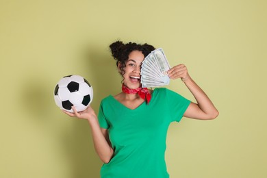 Photo of Happy woman with money and soccer ball on pale green background