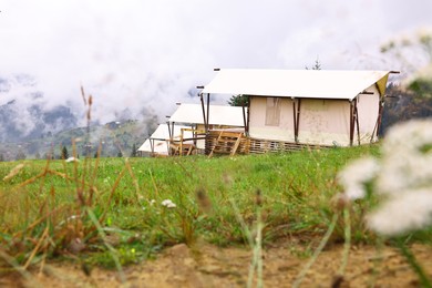 Photo of Many tents and forest covered with fog in mountains. Glamping site