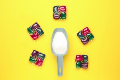 Photo of Laundry capsules and detergent powder on yellow background, flat lay