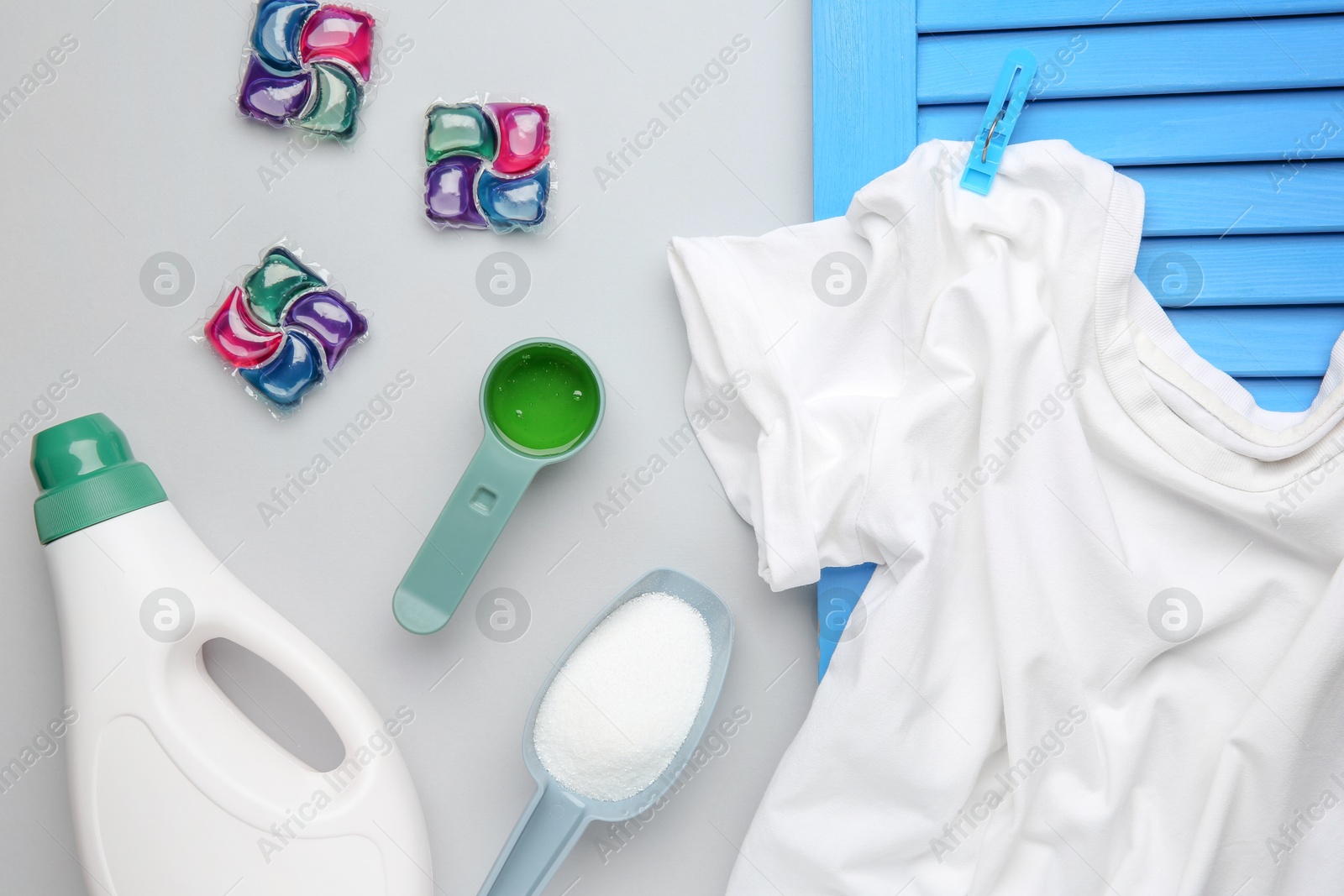 Photo of Different laundry detergents and t-shirt on grey background, flat lay