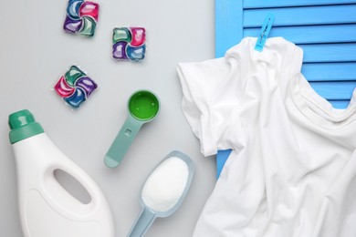 Photo of Different laundry detergents and t-shirt on grey background, flat lay