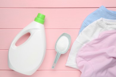 Photo of Laundry detergents and t-shirts on pink wooden table, flat lay