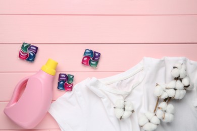 Photo of Laundry detergent in bottle, pods, cotton flowers and t-shirt on pink wooden table, flat lay