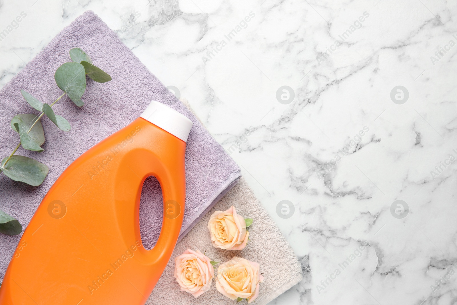 Photo of Laundry detergent in bottle, rose flowers, eucalyptus branches and towels on white marble table, top view. Space for text