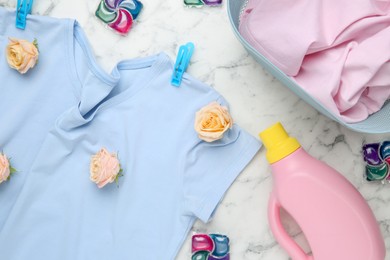 Photo of Flat lay composition with laundry detergents, rose flowers and t-shirts on white marble table