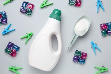 Photo of Different laundry detergents and clothespins on grey table, flat lay