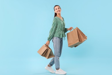 Smiling woman with shopping bags on light blue background