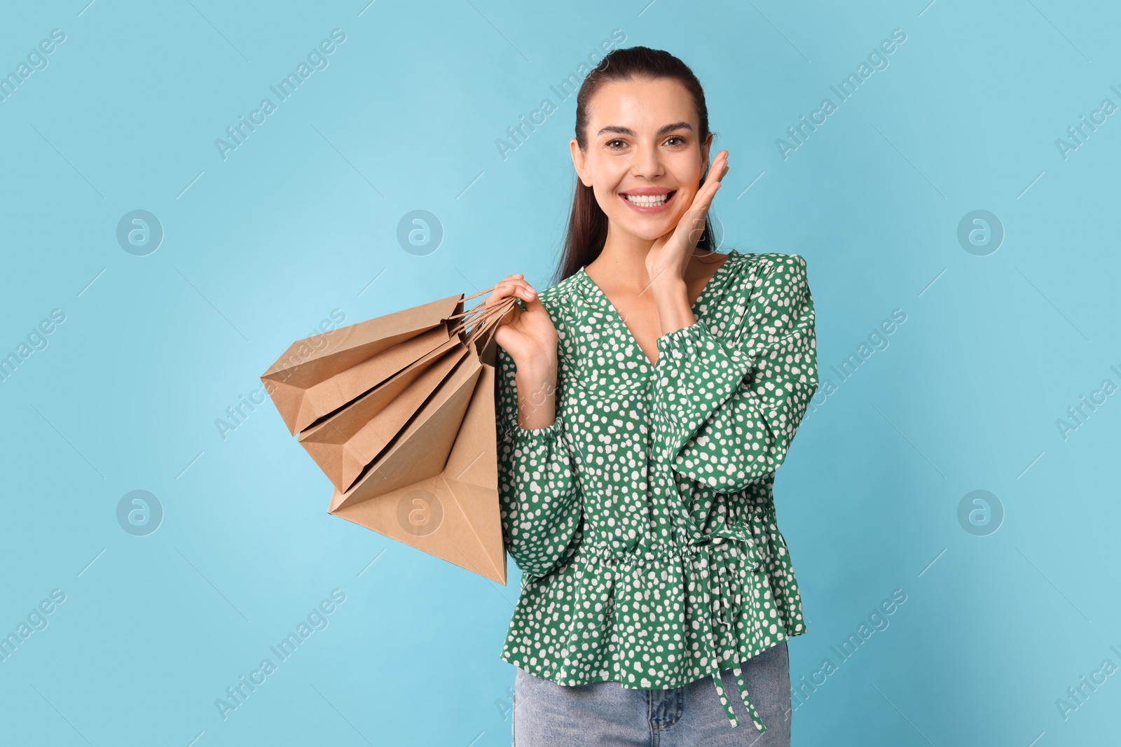 Photo of Smiling woman with shopping bags on light blue background