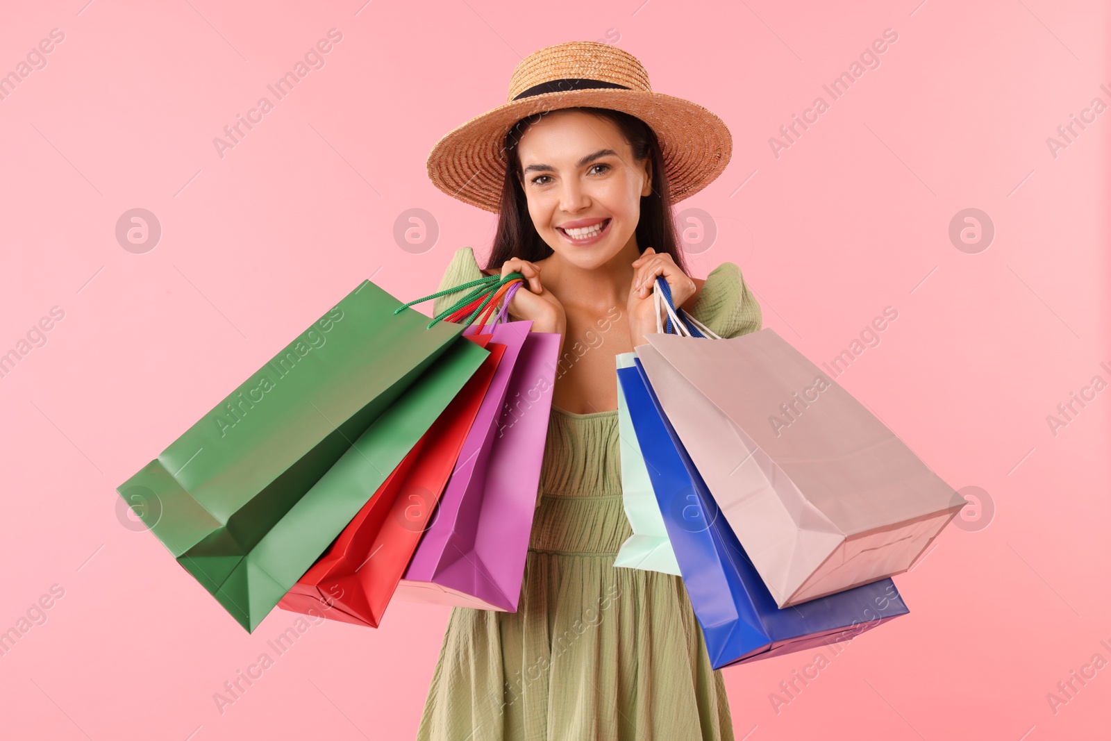 Photo of Smiling woman with colorful shopping bags on pink background