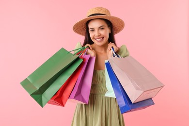 Photo of Smiling woman with colorful shopping bags on pink background