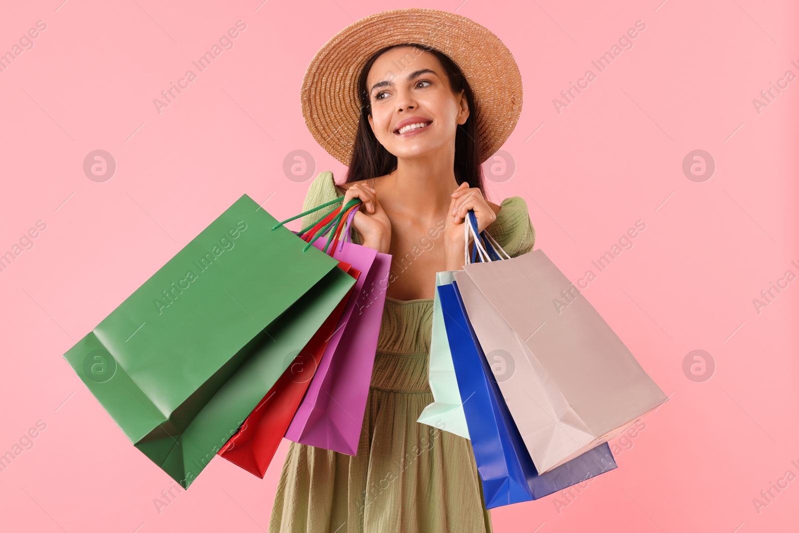 Photo of Smiling woman with colorful shopping bags on pink background