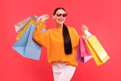 Smiling woman with colorful shopping bags on red background