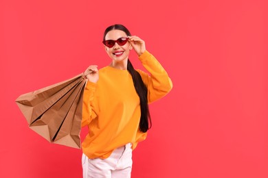 Smiling woman with shopping bags on red background. Space for text