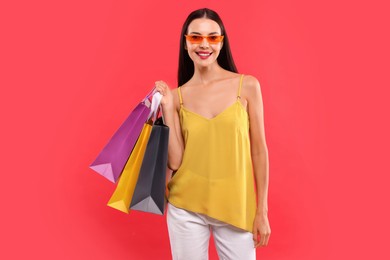 Photo of Smiling woman with colorful shopping bags on red background