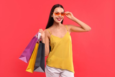 Photo of Smiling woman with colorful shopping bags on red background