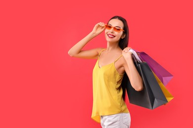 Photo of Smiling woman with colorful shopping bags on red background. Space for text