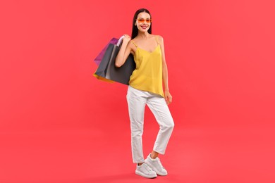 Photo of Smiling woman with colorful shopping bags on red background