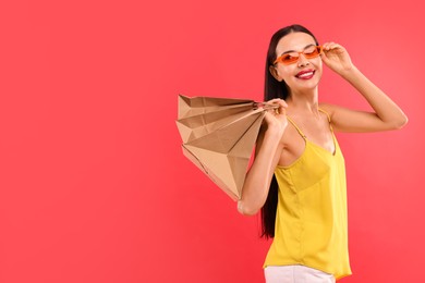 Smiling woman with shopping bags on red background. Space for text