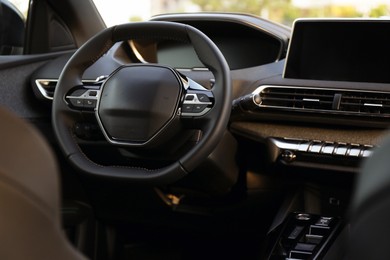 Photo of Steering wheel and dashboard inside of modern luxury car, closeup