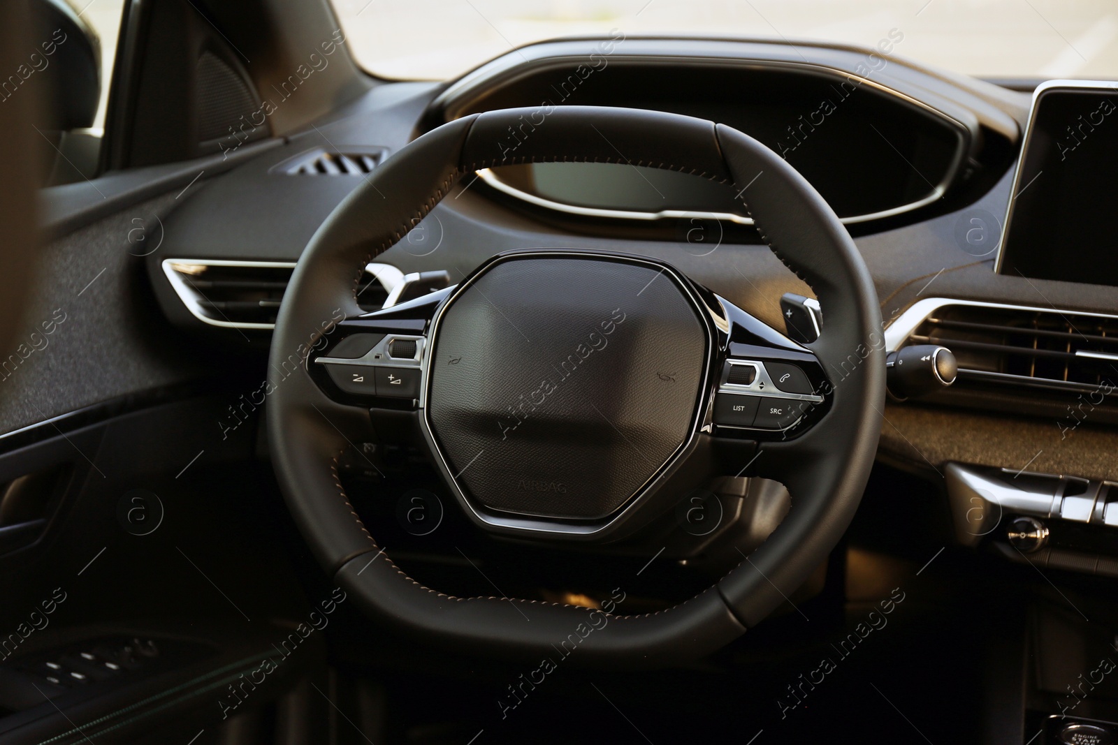 Photo of Steering wheel and dashboard inside of modern luxury car, closeup