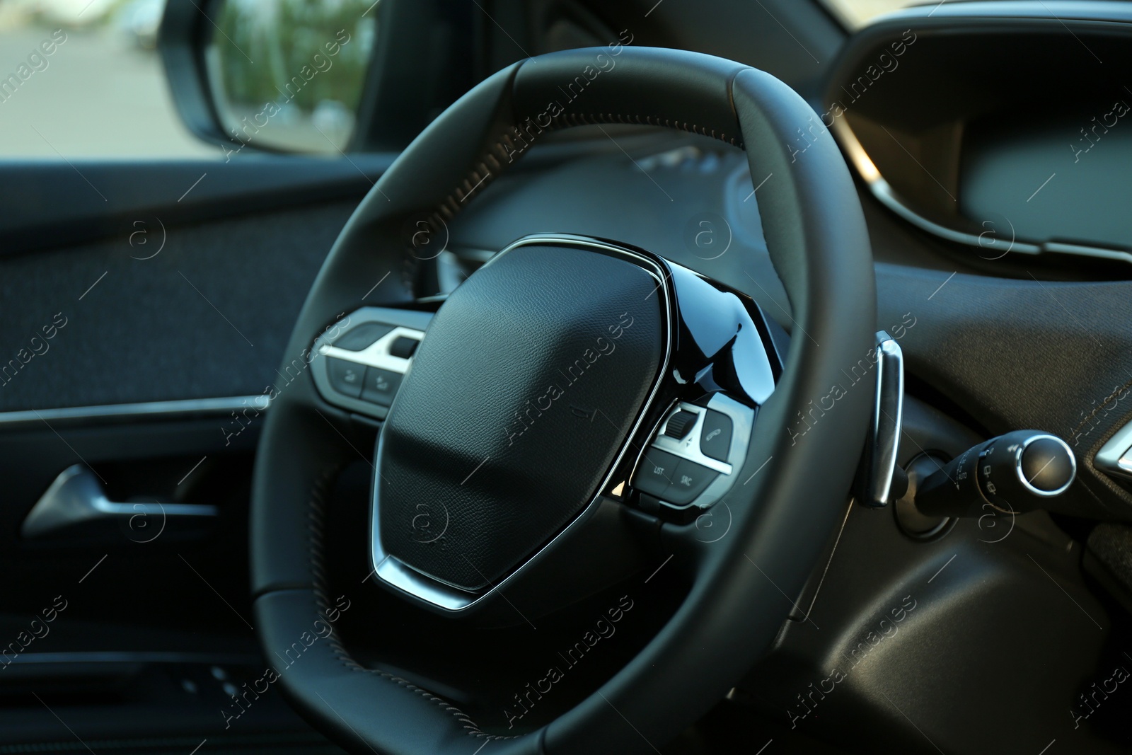 Photo of Steering wheel and dashboard inside of modern luxury car, closeup