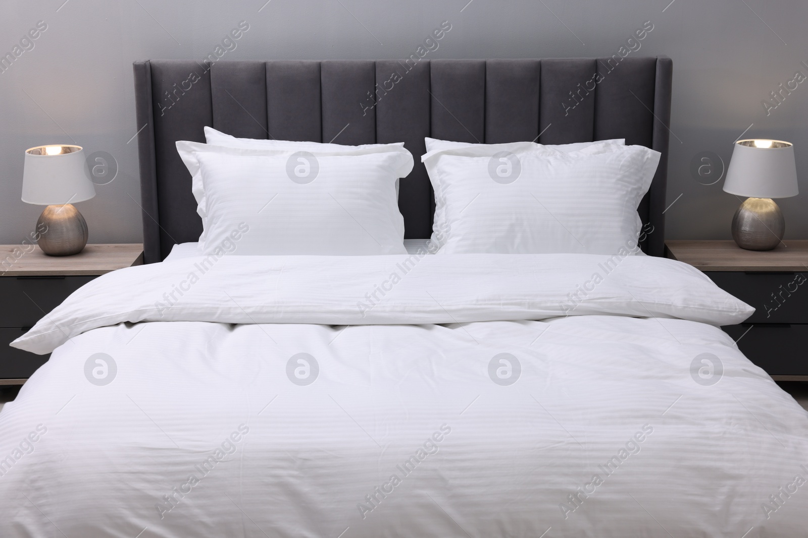 Photo of Bed with clean linens and pillows indoors