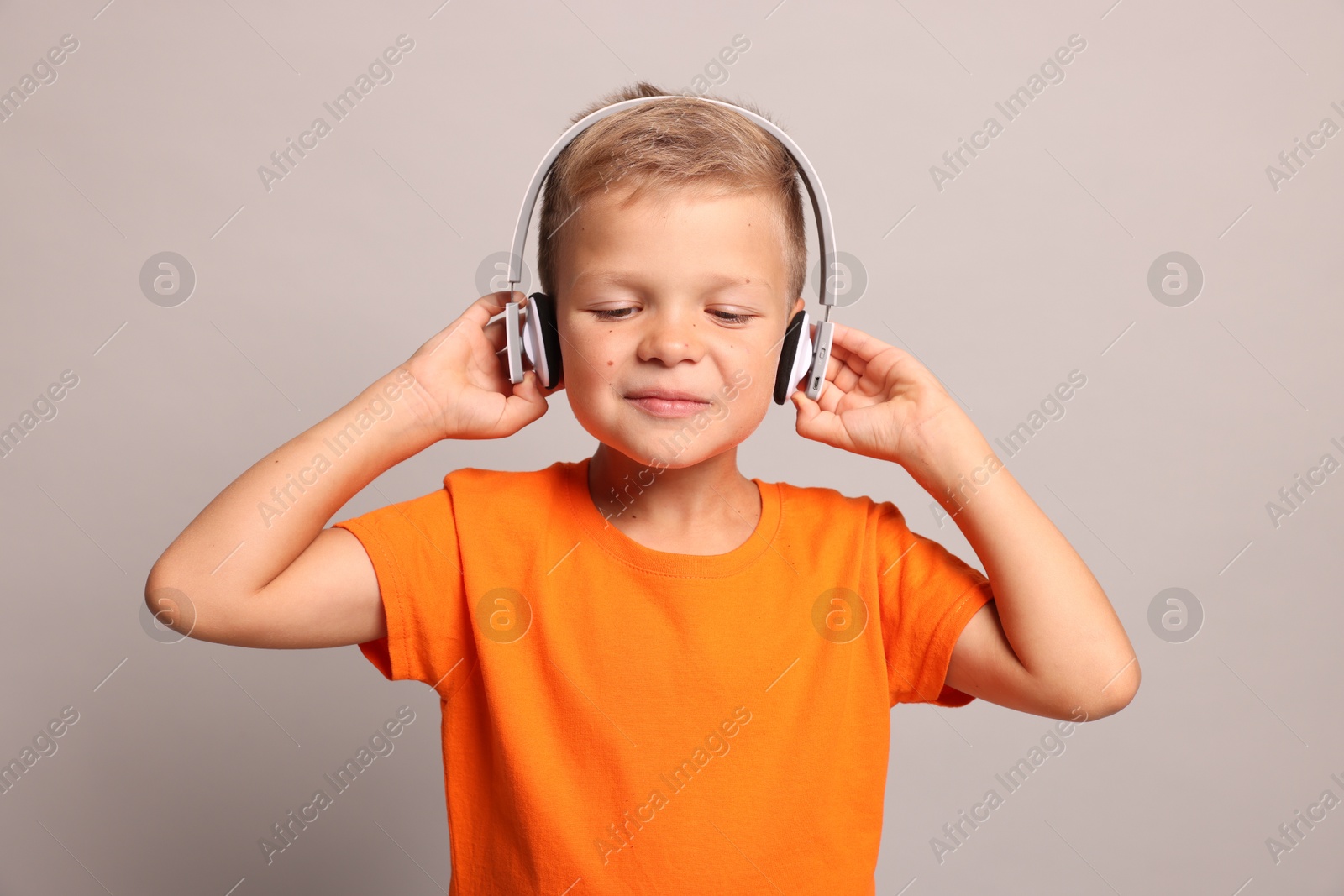 Photo of Little boy listening to music on light grey background