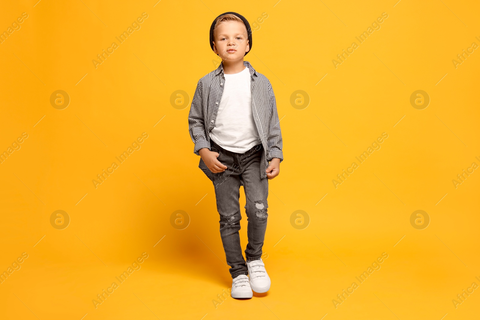 Photo of Full length portrait of little boy with stylish clothes on orange background