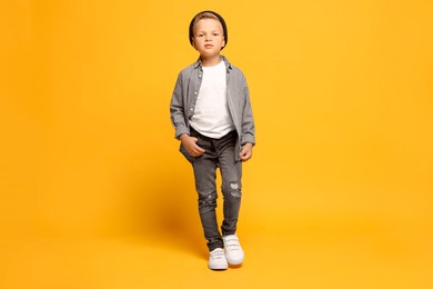 Photo of Full length portrait of little boy with stylish clothes on orange background