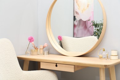 Mirror, dressing table and armchair indoors. Interior design