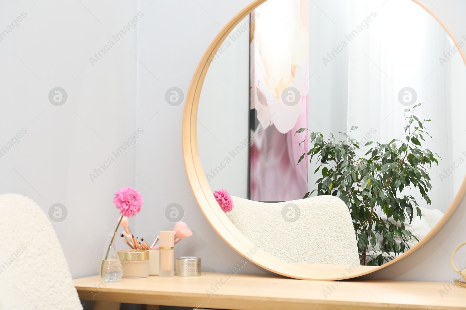 Photo of Dressing table with mirror, cosmetic products and flower indoors. Interior design