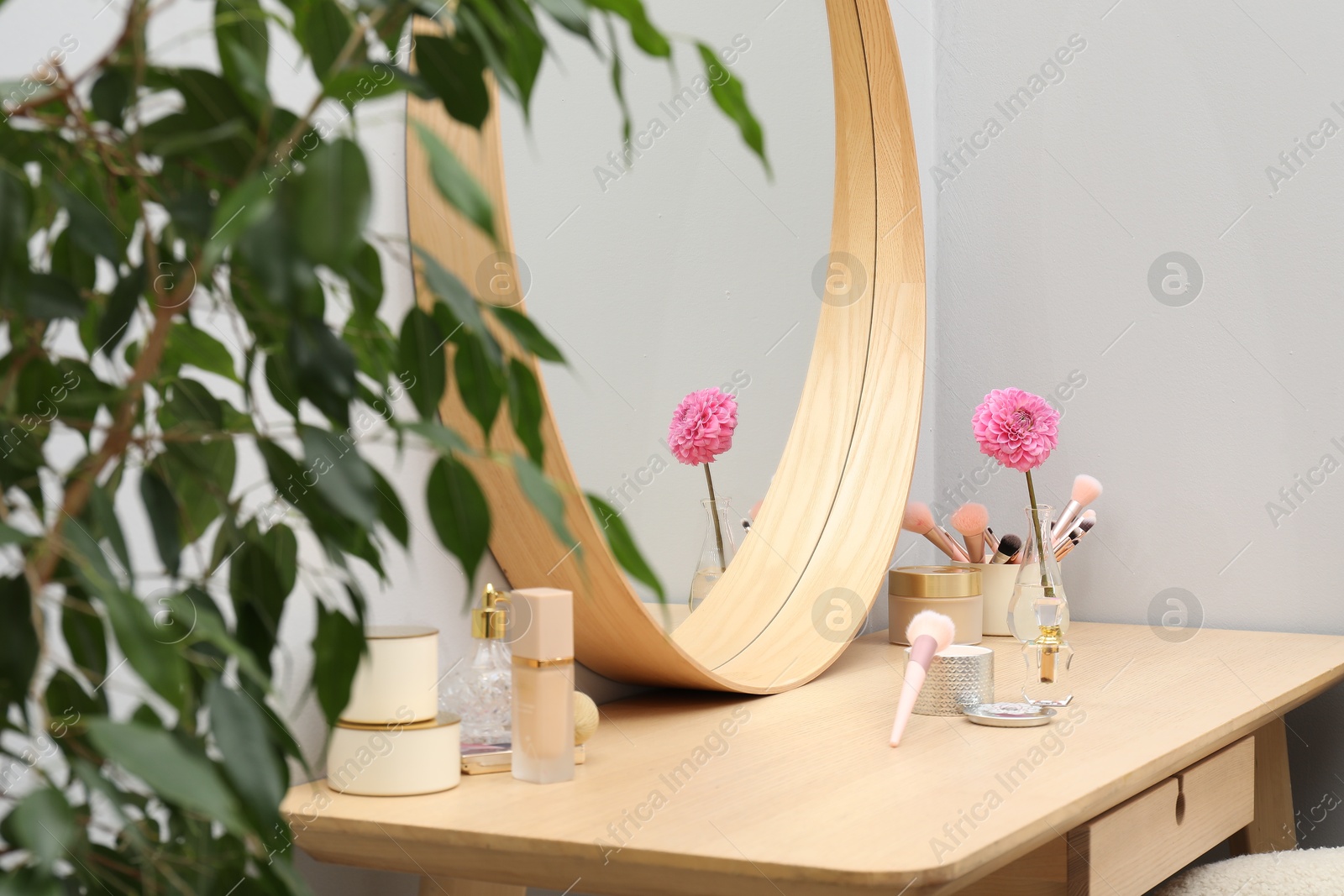 Photo of Dressing table with mirror, cosmetic products and flower indoors. Interior design