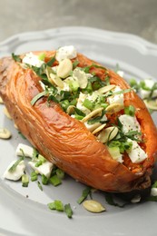 Photo of Tasty cooked sweet potato with feta cheese, pumpkin seeds and green onion on table, closeup