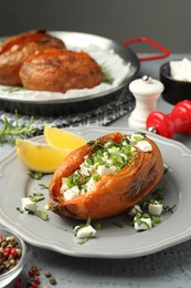 Photo of Tasty cooked sweet potato with feta cheese, lemon and green onion on table, closeup