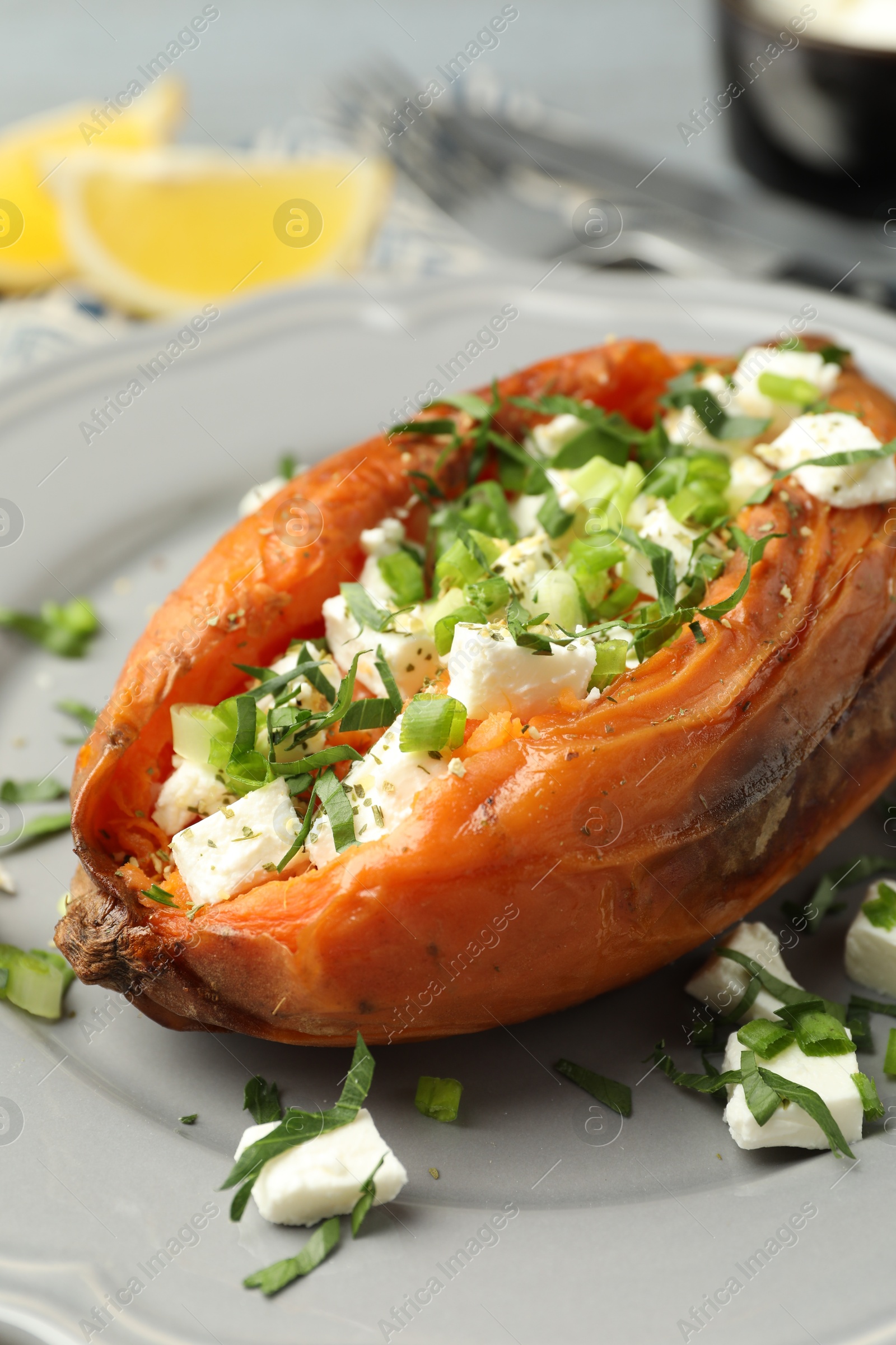 Photo of Tasty cooked sweet potato with feta cheese and green onion on table, closeup