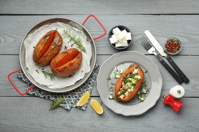 Photo of Tasty cooked sweet potatoes served with feta cheese on grey wooden table, top view