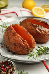 Photo of Tasty cooked sweet potatoes served with rosemary on table, closeup