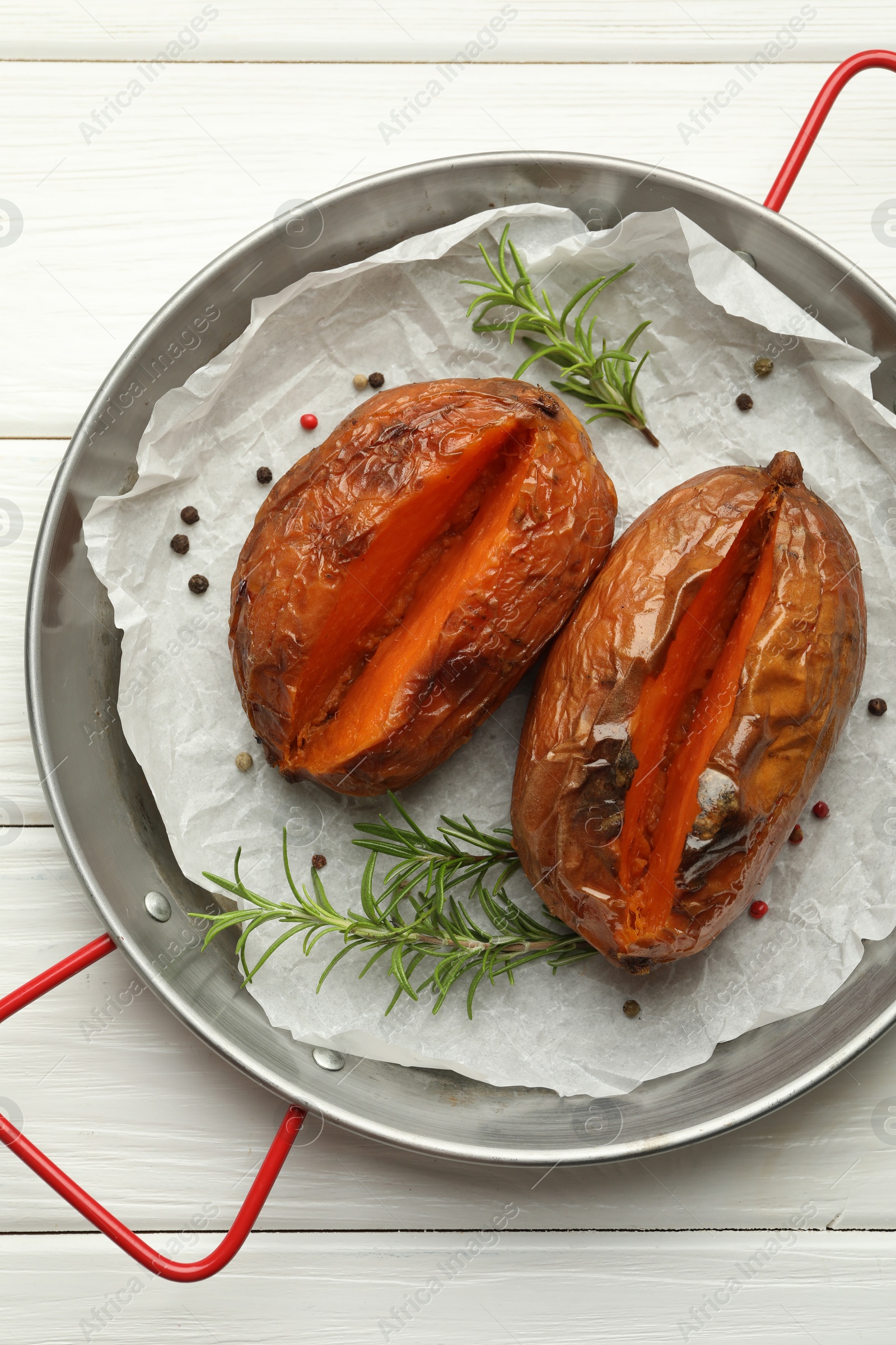 Photo of Tasty cooked sweet potatoes with rosemary on white wooden table, top view