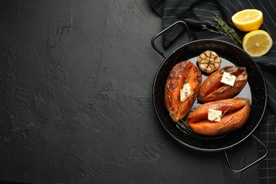 Photo of Tasty cooked sweet potatoes with feta cheese, garlic, thyme and lemon on black table, top view. Space for text