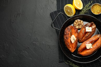 Tasty cooked sweet potatoes with feta cheese, garlic, thyme and lemon on black table, top view. Space for text