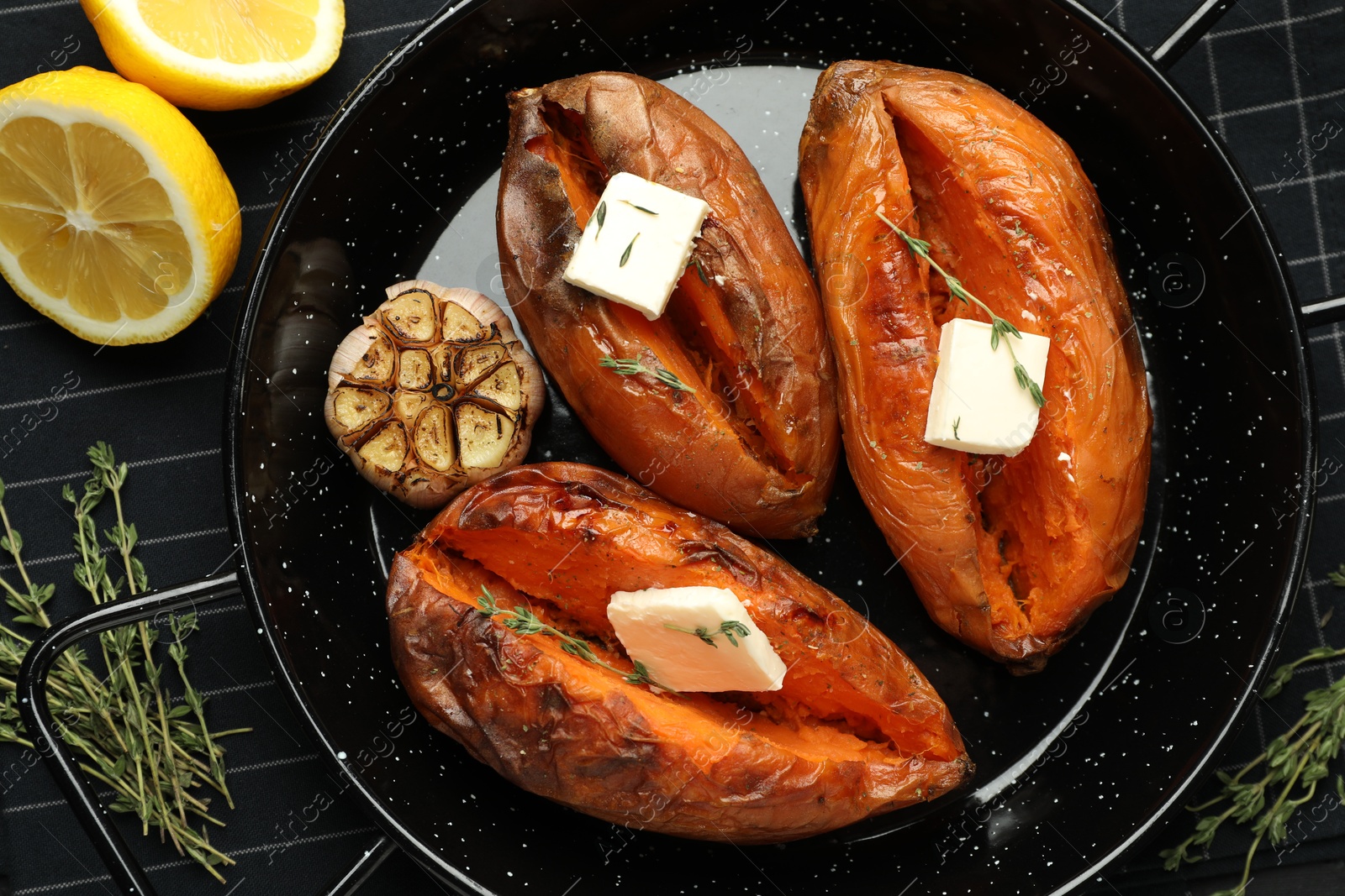 Photo of Tasty cooked sweet potatoes with feta cheese, garlic, thyme and lemon on table, top view